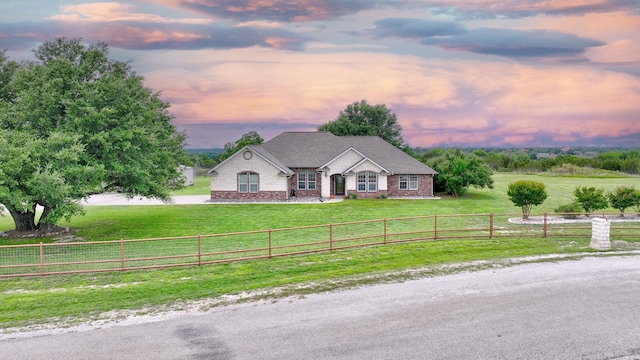 view of front of home with a lawn and a rural view