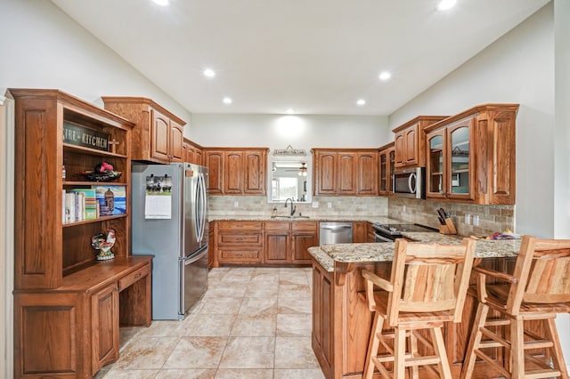 kitchen featuring sink, a kitchen breakfast bar, stainless steel appliances, decorative backsplash, and kitchen peninsula