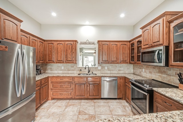 kitchen with stainless steel appliances, tasteful backsplash, light stone countertops, and sink