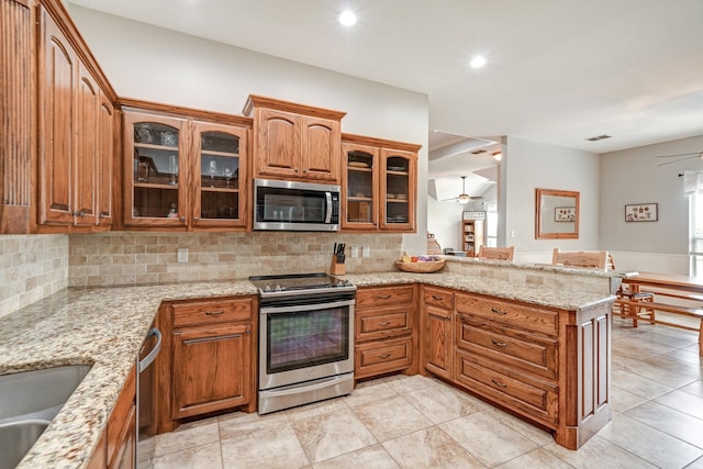 kitchen with appliances with stainless steel finishes, light stone counters, ceiling fan, and kitchen peninsula