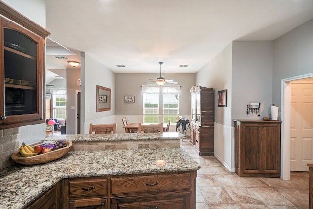 kitchen featuring light stone counters, ceiling fan, and kitchen peninsula