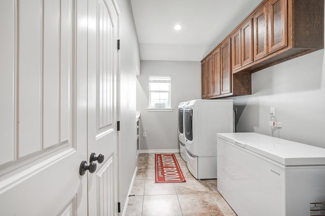 clothes washing area featuring cabinets, separate washer and dryer, and light tile patterned floors