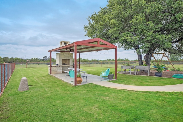 view of play area featuring an outdoor brick fireplace, a yard, and a patio