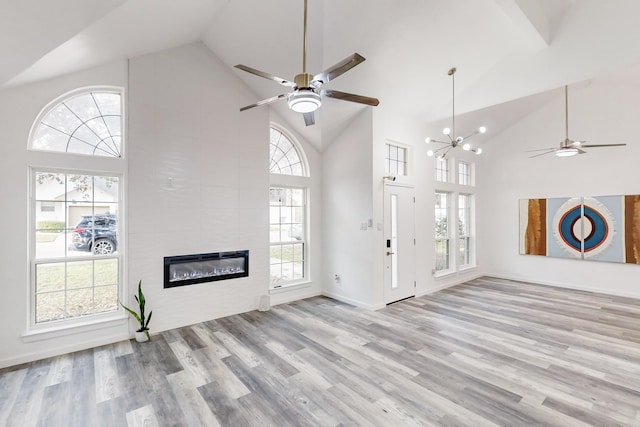 unfurnished living room featuring a fireplace, light hardwood / wood-style flooring, high vaulted ceiling, and plenty of natural light