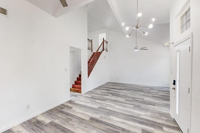 interior space featuring ceiling fan with notable chandelier, light wood-type flooring, and high vaulted ceiling