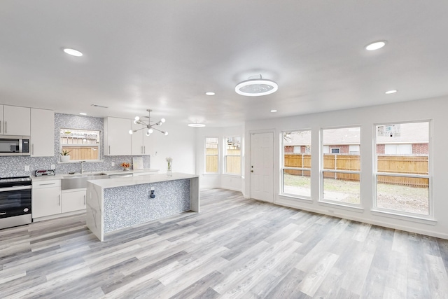 kitchen with white cabinets, a healthy amount of sunlight, hanging light fixtures, and appliances with stainless steel finishes