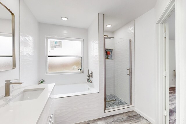 bathroom with separate shower and tub, hardwood / wood-style floors, and vanity