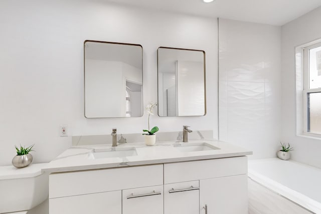 bathroom with a washtub, vanity, a healthy amount of sunlight, and toilet