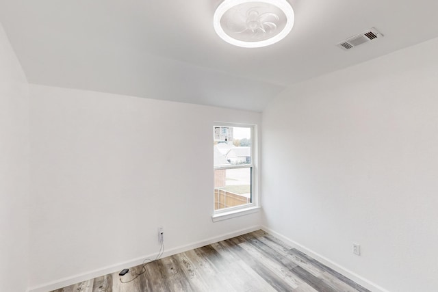 spare room with light hardwood / wood-style floors and lofted ceiling