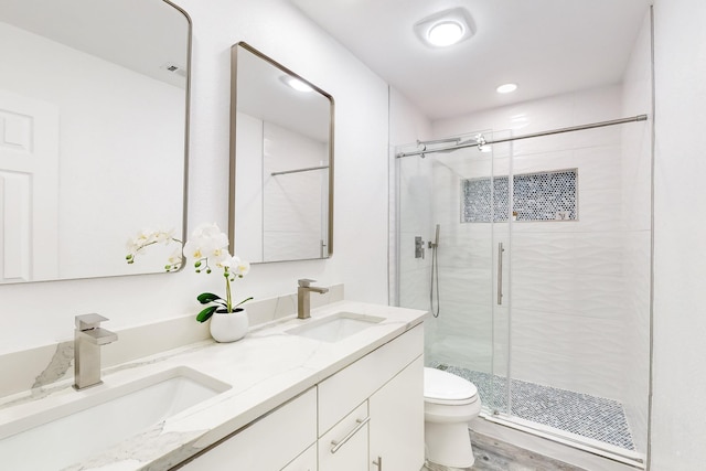 bathroom with hardwood / wood-style floors, vanity, toilet, and a shower with shower door