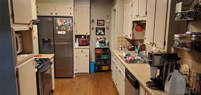 kitchen with sink, light hardwood / wood-style flooring, decorative backsplash, white cabinets, and appliances with stainless steel finishes