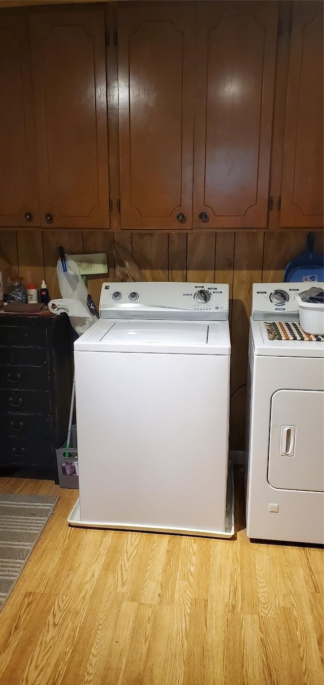 washroom featuring washer and dryer, cabinets, and light wood-type flooring