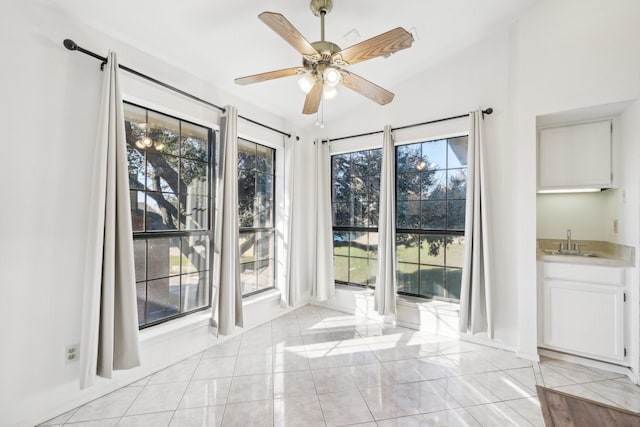 interior space with light tile patterned floors, wet bar, and ceiling fan