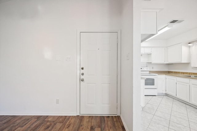 kitchen featuring sink, light hardwood / wood-style flooring, white cabinets, and white electric stove