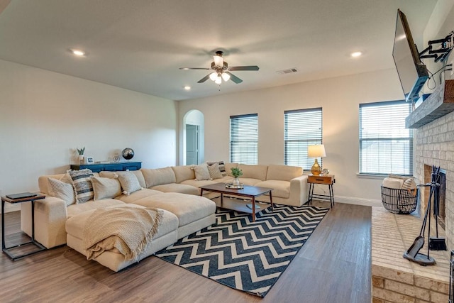 living room with ceiling fan, a fireplace, and wood-type flooring