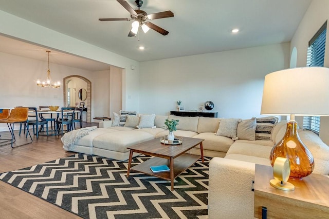 living room featuring plenty of natural light, wood-type flooring, and ceiling fan with notable chandelier