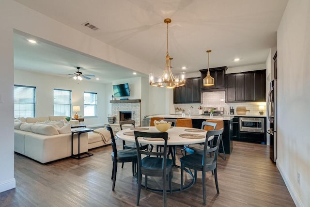 dining area with a fireplace, hardwood / wood-style floors, ceiling fan with notable chandelier, and sink