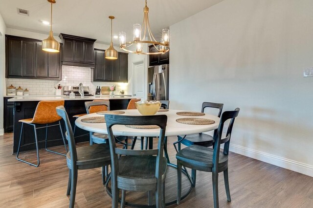 kitchen featuring a kitchen bar, stainless steel fridge with ice dispenser, a kitchen island with sink, and wood-type flooring