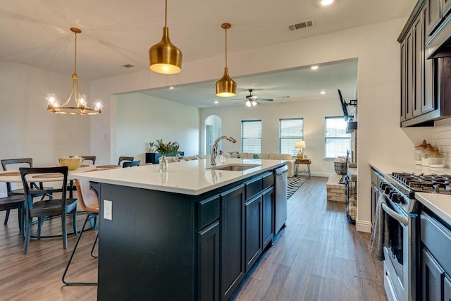 kitchen featuring sink, ceiling fan with notable chandelier, a breakfast bar, a center island with sink, and appliances with stainless steel finishes