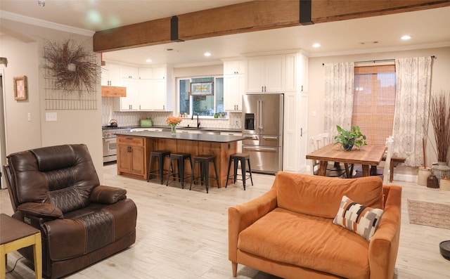 living room with beam ceiling, sink, ornamental molding, and light wood-type flooring