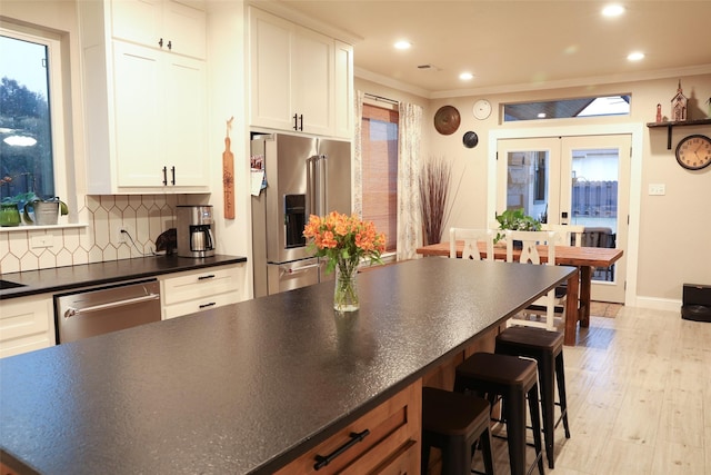 kitchen with white cabinetry, backsplash, ornamental molding, and stainless steel appliances