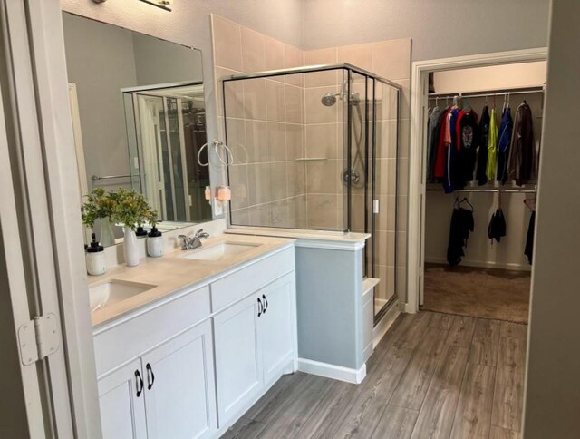 bathroom featuring wood-type flooring, a shower with shower door, and vanity