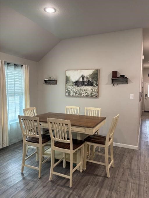 dining room with vaulted ceiling and dark wood-type flooring