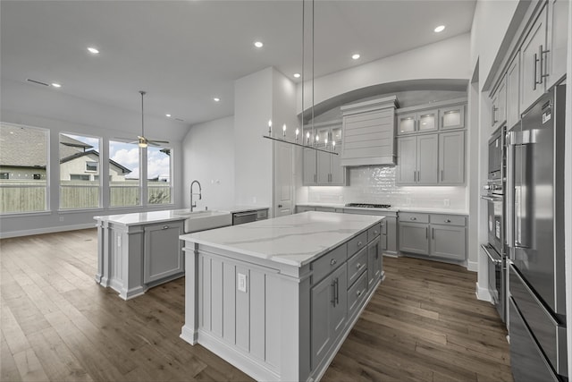 kitchen with gray cabinetry, sink, a kitchen island, and decorative light fixtures