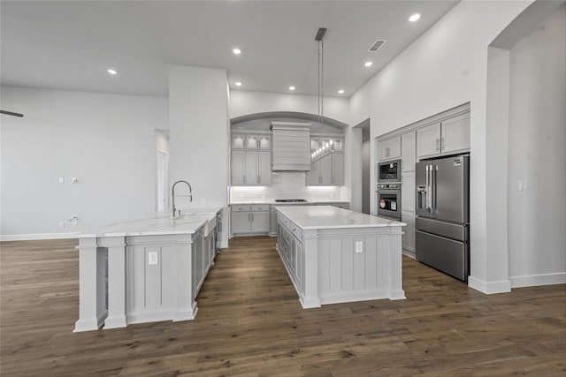 kitchen featuring appliances with stainless steel finishes, pendant lighting, a center island with sink, gray cabinets, and dark hardwood / wood-style floors