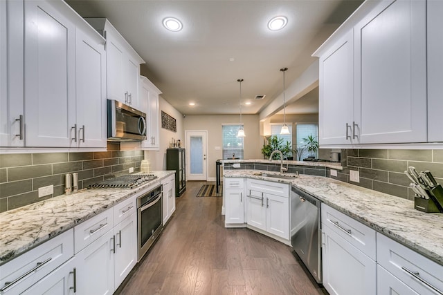 kitchen featuring appliances with stainless steel finishes, dark hardwood / wood-style flooring, sink, white cabinets, and hanging light fixtures