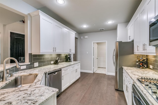 kitchen featuring light stone countertops, white cabinetry, sink, stainless steel appliances, and dark hardwood / wood-style flooring