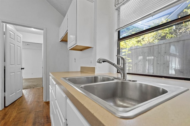 kitchen with dark hardwood / wood-style flooring, sink, vaulted ceiling, and white cabinets