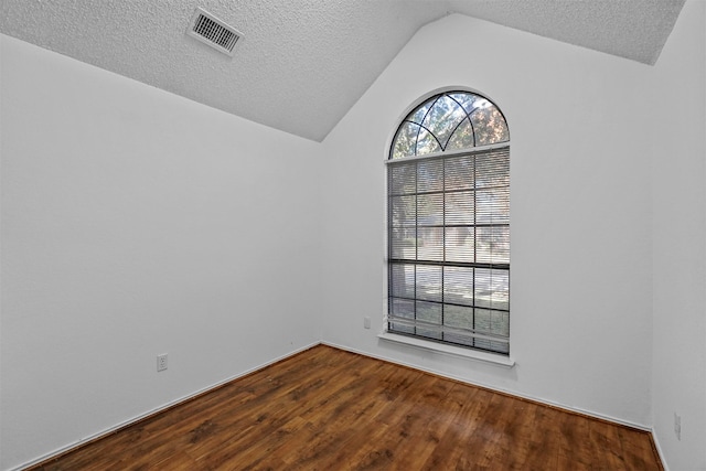 unfurnished room with a textured ceiling, vaulted ceiling, and wood-type flooring