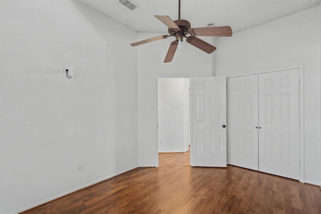 unfurnished bedroom featuring hardwood / wood-style flooring, vaulted ceiling, a closet, and ceiling fan