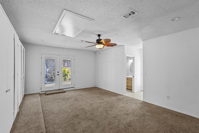 empty room with light colored carpet, a textured ceiling, and french doors