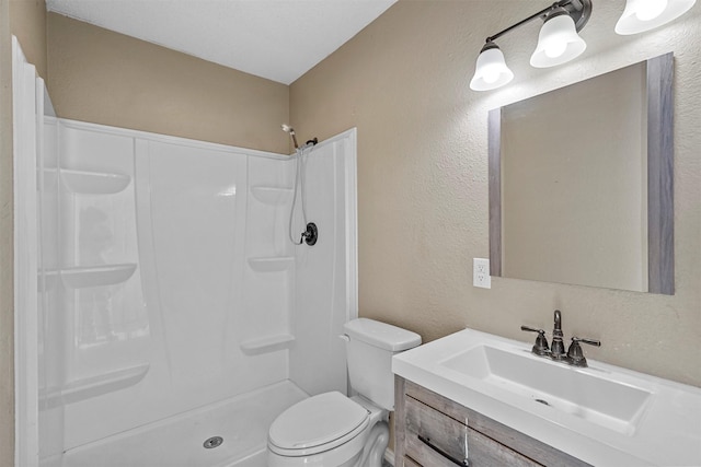 bathroom featuring toilet, vanity, and walk in shower