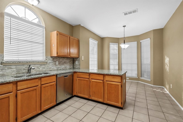 kitchen with light stone countertops, dishwasher, sink, kitchen peninsula, and pendant lighting