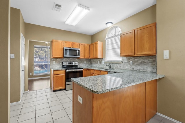 kitchen with backsplash, sink, appliances with stainless steel finishes, light stone counters, and kitchen peninsula