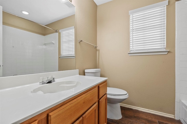 full bathroom with tiled shower / bath, vanity, wood-type flooring, and toilet