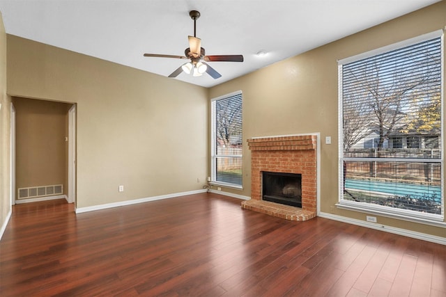 unfurnished living room featuring dark hardwood / wood-style floors, ceiling fan, and a brick fireplace