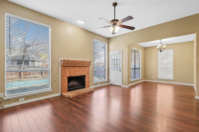 unfurnished living room featuring a fireplace, hardwood / wood-style floors, and ceiling fan with notable chandelier