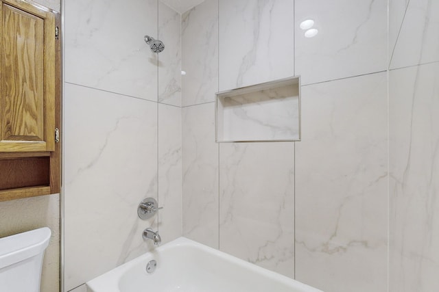 bathroom featuring tiled shower / bath combo and toilet