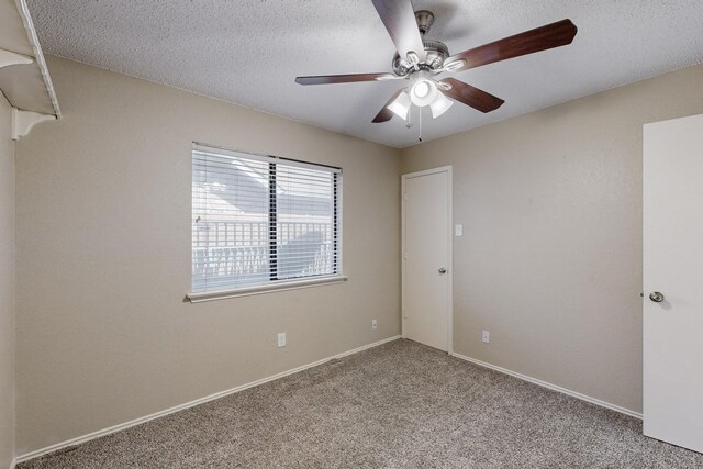 carpeted spare room featuring a textured ceiling and ceiling fan