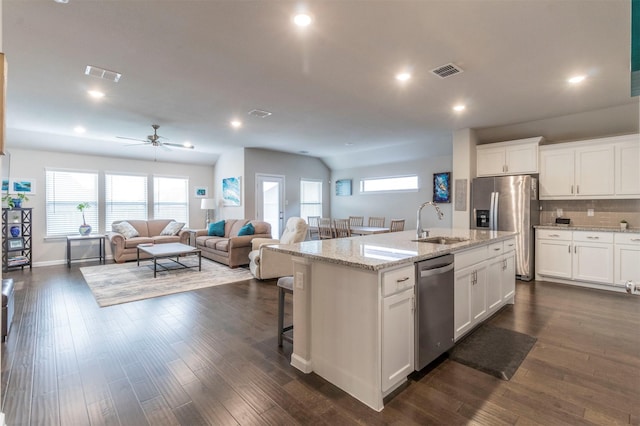 kitchen with white cabinets, appliances with stainless steel finishes, dark hardwood / wood-style flooring, and a center island with sink