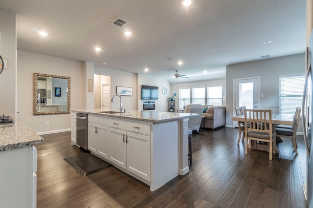 kitchen with light stone counters, sink, dark hardwood / wood-style floors, white cabinetry, and an island with sink