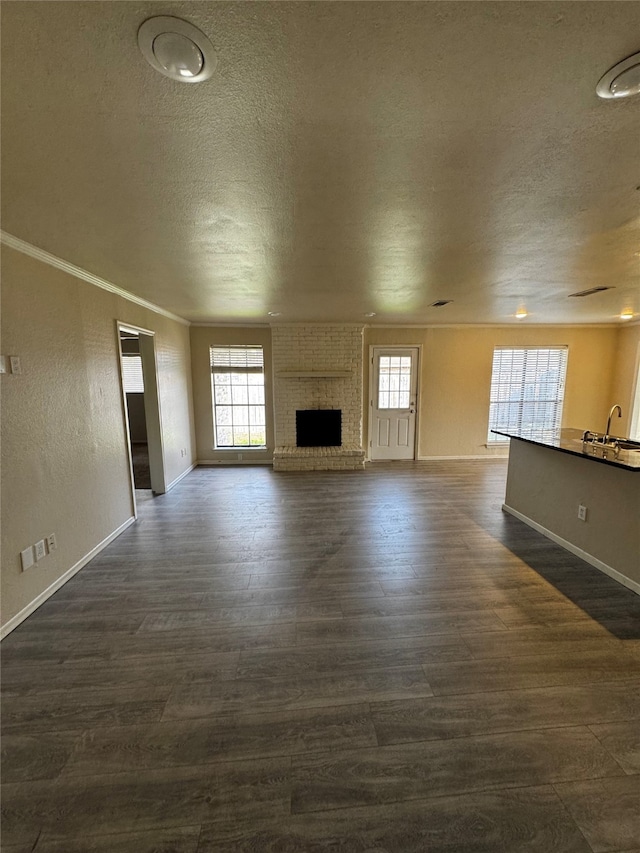 unfurnished living room featuring a textured ceiling, a fireplace, dark hardwood / wood-style floors, and ornamental molding