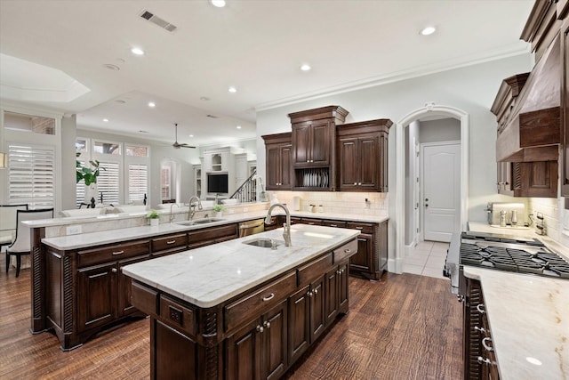 kitchen featuring backsplash, a kitchen island with sink, sink, and dark wood-type flooring