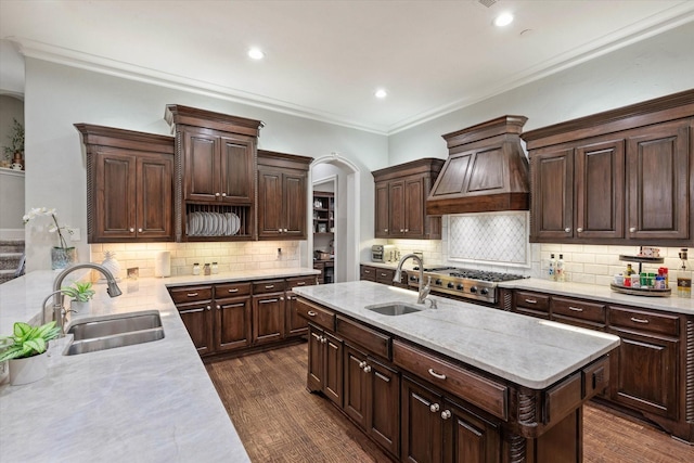 kitchen with a center island with sink, crown molding, and sink