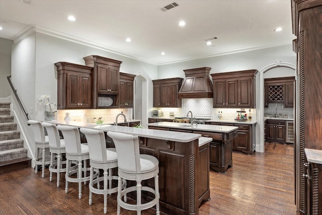 kitchen with dark brown cabinets, backsplash, dark hardwood / wood-style floors, and custom exhaust hood