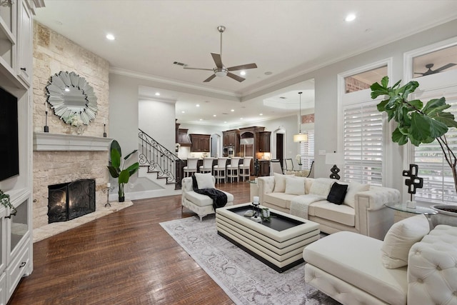 living room with ceiling fan, a fireplace, ornamental molding, and hardwood / wood-style flooring